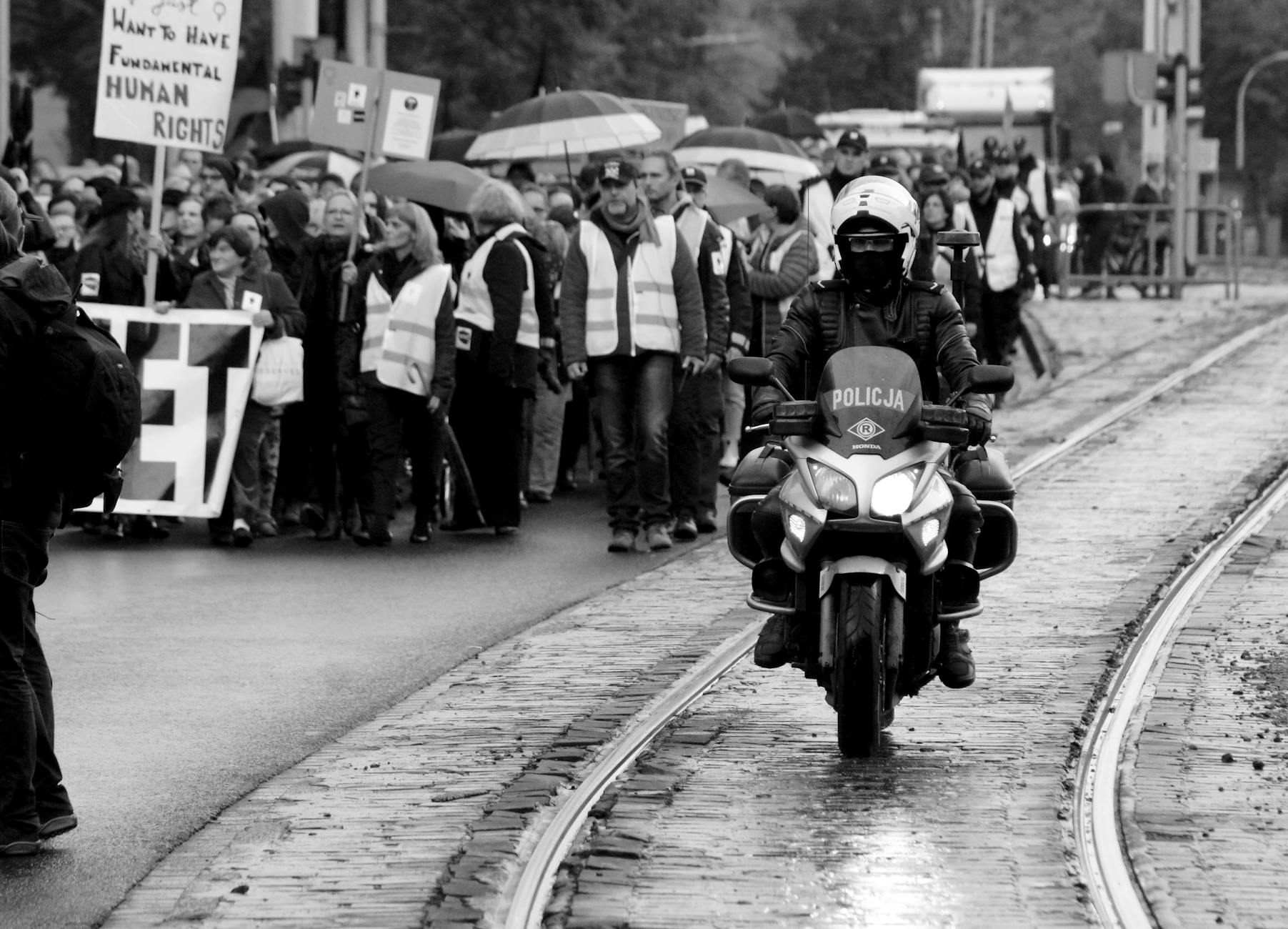 Ilustracja przedstawiająca stadion Jagiellonii Białystok oraz pociąg na tle nowoczesnej infrastruktury kolejowej, symbolizująca protest i modernizację